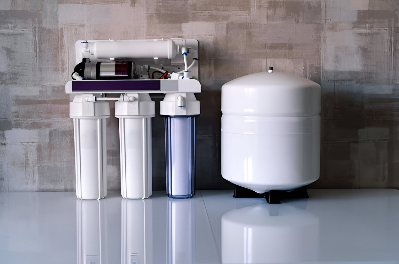 A reverse osmosis water filtration system featuring carbon filtration with three filter cartridges and a separate storage tank, placed on a white surface against a tiled wall.