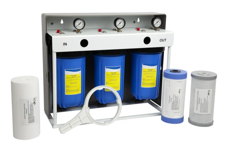 Three-stage water filtration system with pressure gauges, labeled "IN" and "OUT," shown with replacement filter cartridges and a filter wrench in front.