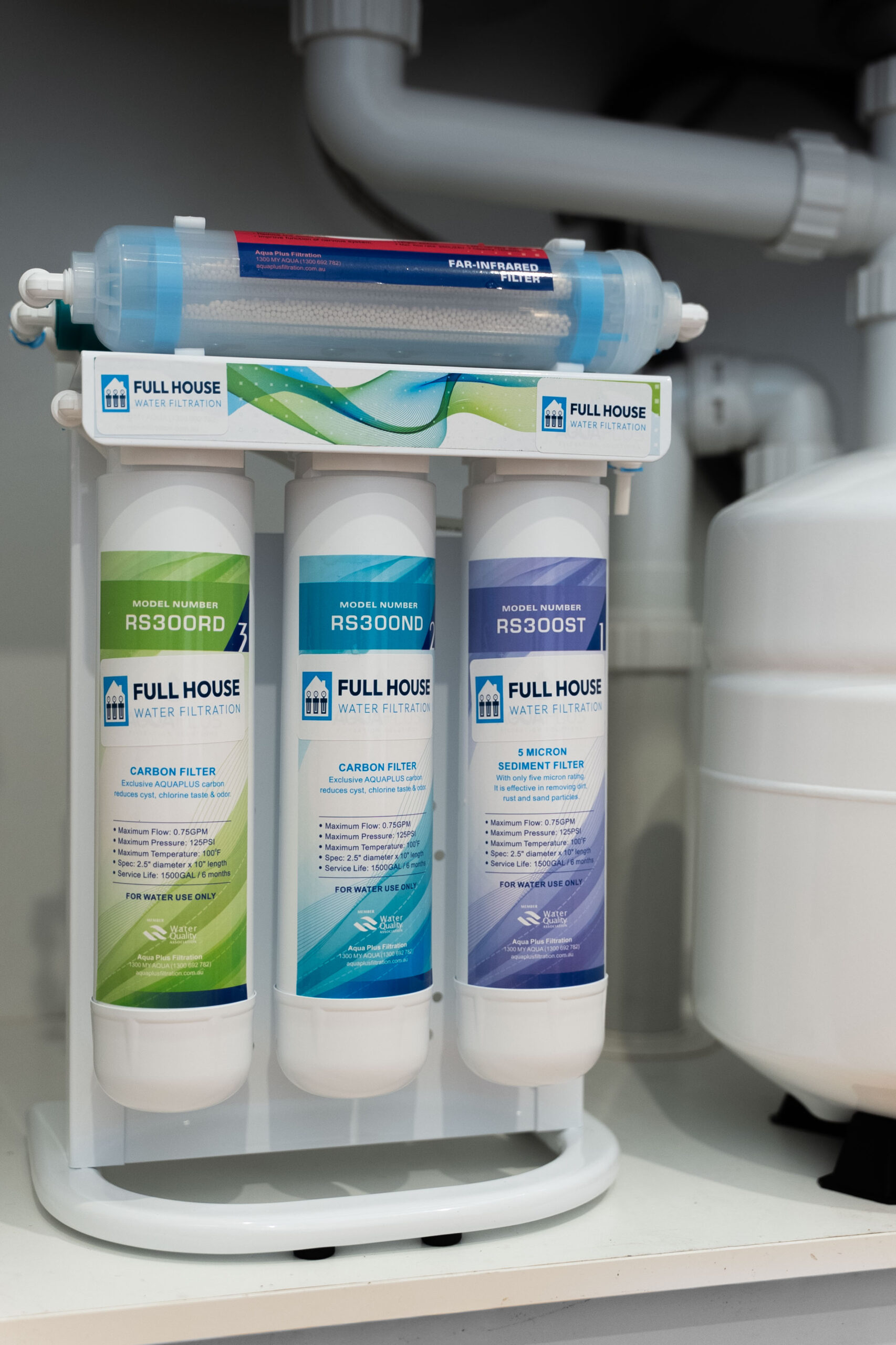 Under-sink three-cartridge water filtration system with branded 'Full House Water Filtration' labels and a blue filter housing above.